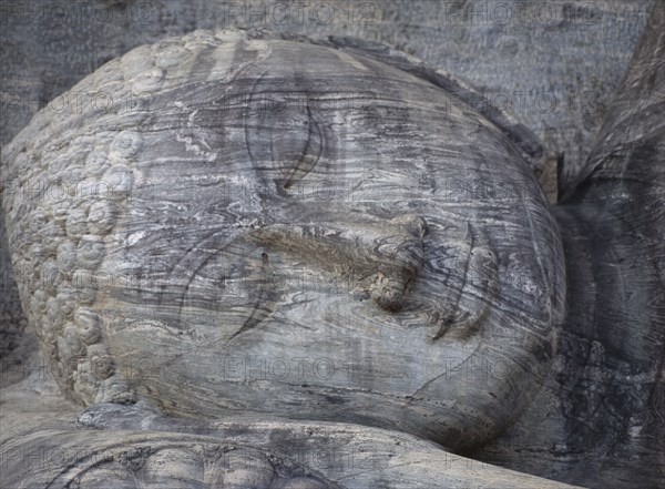 SRI LANKA, Polonnaruwa, Gal Vihara.  Mid twelth century reclining Buddha figure shown at the moment of entry into nirvana and carved from granite.  Detail of head and face.