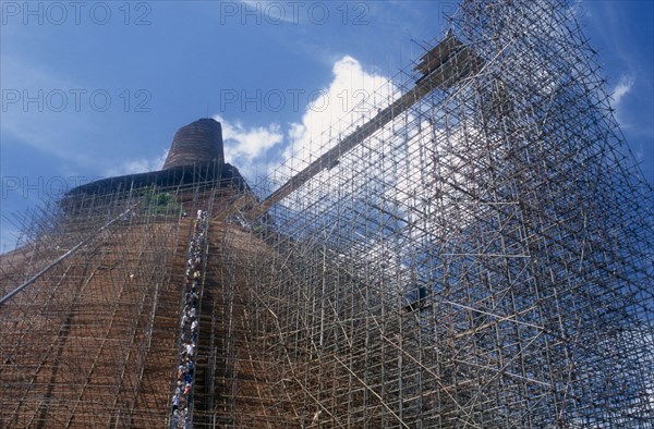 20045345 SRI LANKA  Anuradhapura Jetavanarama dagoba.  Huge brick dome undergoing reconstruction.  Line of workers on network of scaffolding covering exterior.
