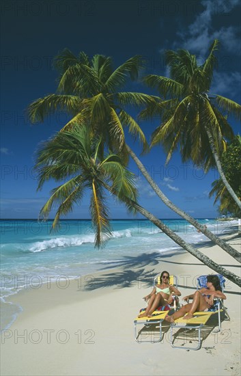 WEST INDIES, Barbados, Christ Church, Worthing beach with tourists sunbathing on loungers