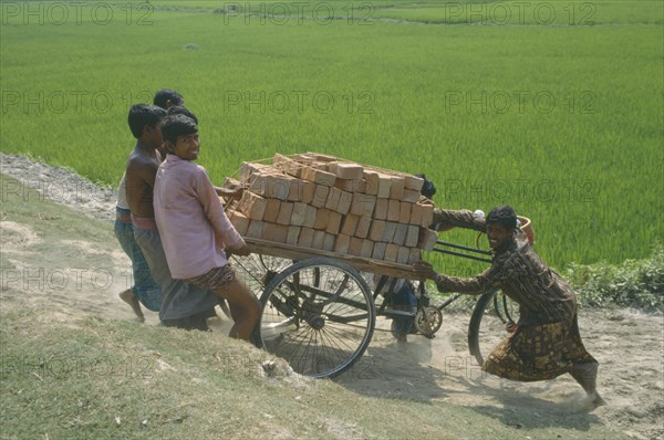 BANGLADESH, Agriculture, Group of men transporting load of bricks using three wheel bicycle with wooden platform.