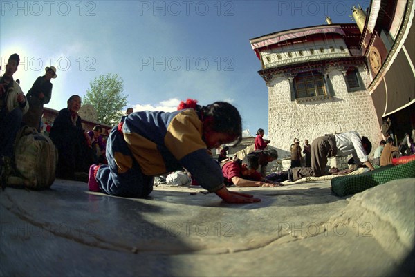 CHINA, Tibet, Lhasa, Wide angle view of  people prostrating themselves outside the Jokhang Temple