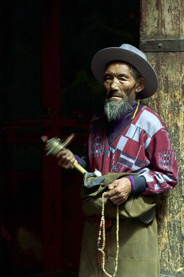 CHINA, Tibet, Lhasa, Portrait of a man spinning a mini Prayer Wheel at the Jokhang Temple