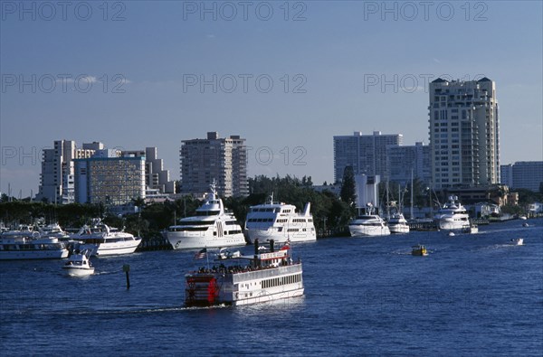 USA, Florida, Fort Lauderdale, View of Paddle steamer sailing up the intra coastal waterway passing moored yachts with the city skyline beyond