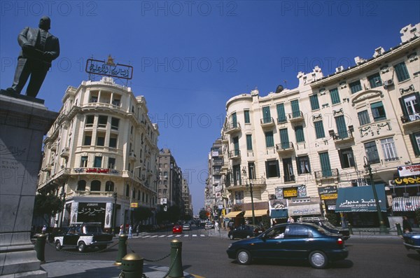 EGYPT, Cairo , Midan Talaat Harb. Traffic on city road lined by cream coloured buildings with green shutters and curved facades