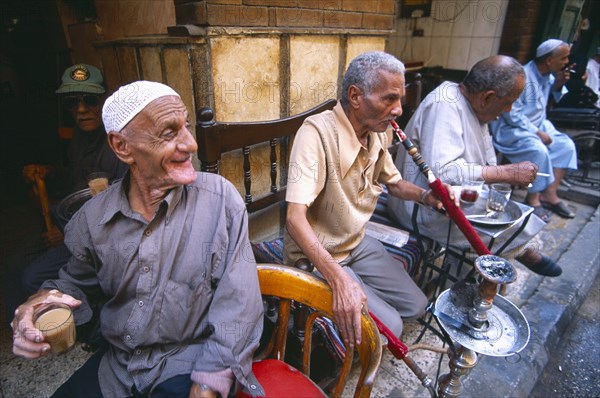 EGYPT, Cairo , Group of men smoking sheesha water pipes and drinking tea in an ahwa or coffee house.