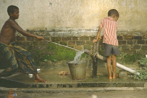 BANGLADESH, Chittagong, Shamshangar, Two young boys drawing water from rowerpump.