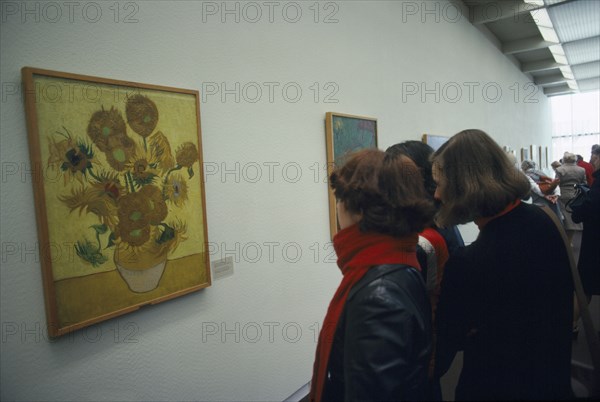 HOLLAND, North, Amsterdam, Visitors inside the Van Gogh Museum looking at painting of Sunflowers.
