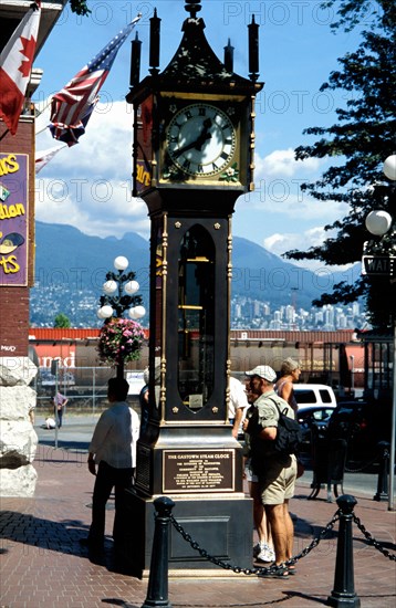 CANADA, Vancouver, Gastown, The Gastown Steam Clock with people reading the inscriptions around the base