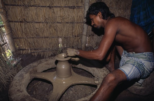 BANGLADESH, Mymensingh, Potter shaping clay pot on wheel.