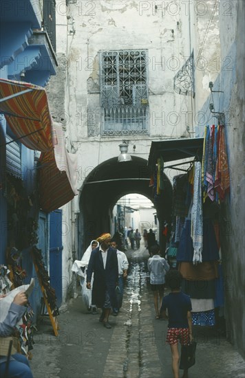 TUNISIA, Tunis, Market scene.  Men and children walking through narrow cobbled street lined with shops.
