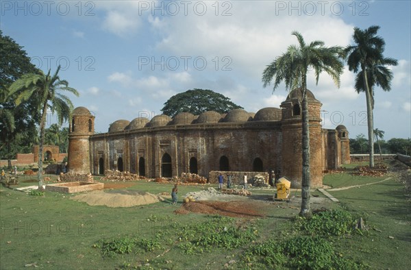 BANGLADESH, Khulna, Bagerhat, Ancient mosque built from bricks and terracotta with construction workers in the foreground.