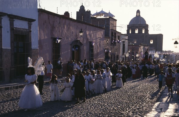MEXICO, San Miguel de Allende, Easter Procession down cobbled street with children dressed in white