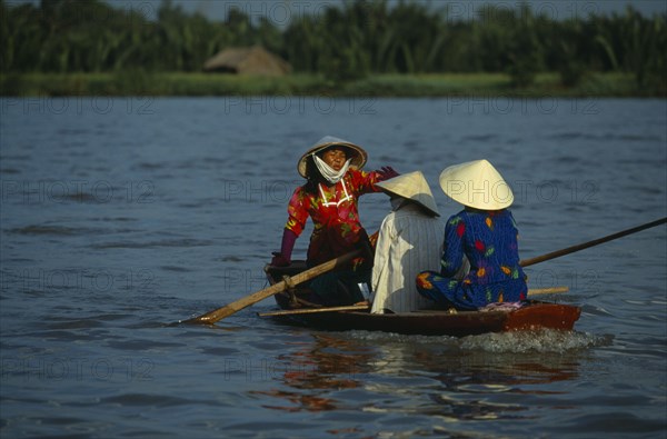 VIETNAM, South, Saigon, Woman paddling a small boat in the traditional way with her feet on the Saigon river