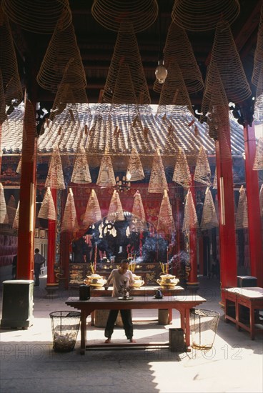 VIETNAM, South, Saigon, Man at an altar below coils of incense at Thien Hau Pagoda