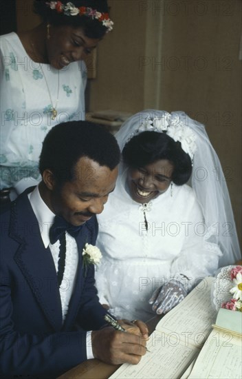 NIGERIA, Religion, Wedding, Ibo wedding ceremony. Couple in traditional western wedding dress signing register.