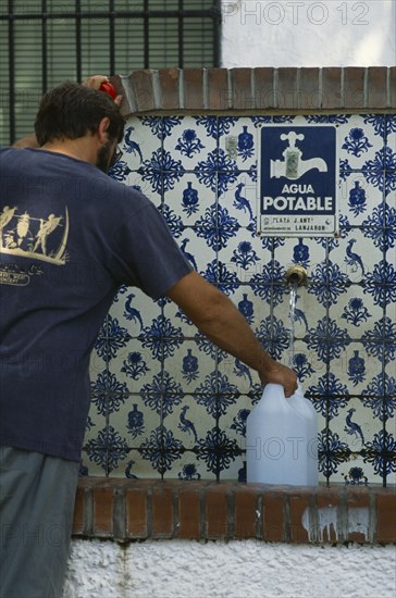 SPAIN, Andalucia, Granada, Lanjaron. Man collecting water from a drinking fountain in this Sierra Nevada town famous for its mineral water