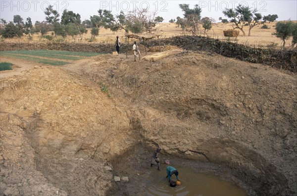 MALI, Pays Dogon, Tirelli, View of deep waterhole and onion fields with farmers working.