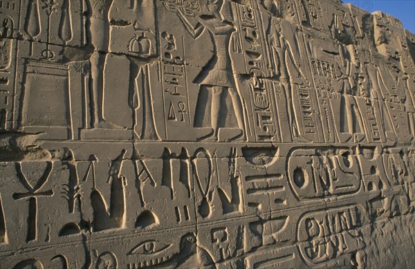 EGYPT, Nile Valley, Karnak, Precinct of Amun.  Detail of relief carving and hieroglyphics along wall of building.