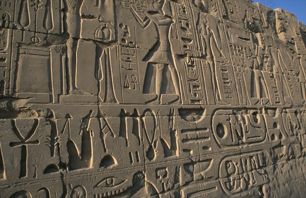 EGYPT, Nile Valley, Karnak, Precinct of Amun. Detail of relief carving and hieroglyphics along wall of building.