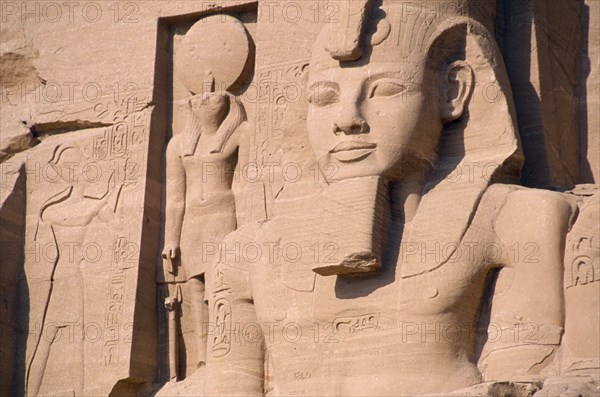 EGYPT, Nile Valley, Abu Simbel, Sun Temple of Ramses II.  Part view of colossi of Ramses II and other statues flanking entrance to temple.