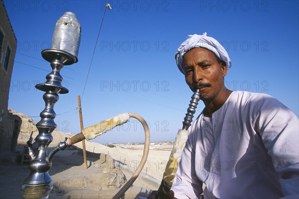 EGYPT, Dra Abul Naga, Man smoking sheesha water pipe.