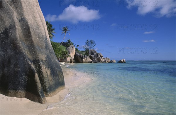 SEYCHELLES, La Digue Island, Anse Source D’Argent. View from behind large rock boulders on golden sandy beach looking along coastline