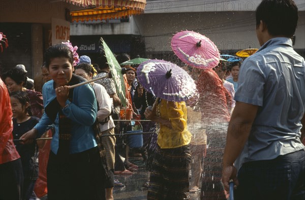 THAILAND, North, Chiang Mai , Girls with umbrellas being sprayed with water on the street during water festival.