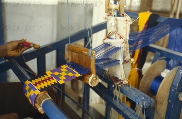 GHANA, Kumasi, Weaving contemporary kente cloth designs.