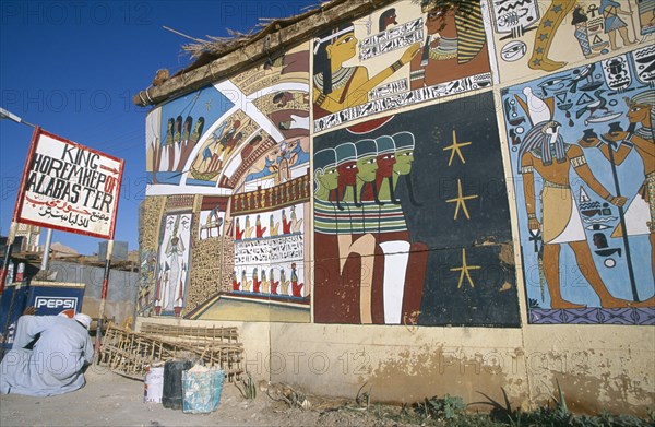 EGYPT, Dra Abul Naga, Painted mural on exterior wall of alabaster shop with man crouched down beside Pepsi sign outside.