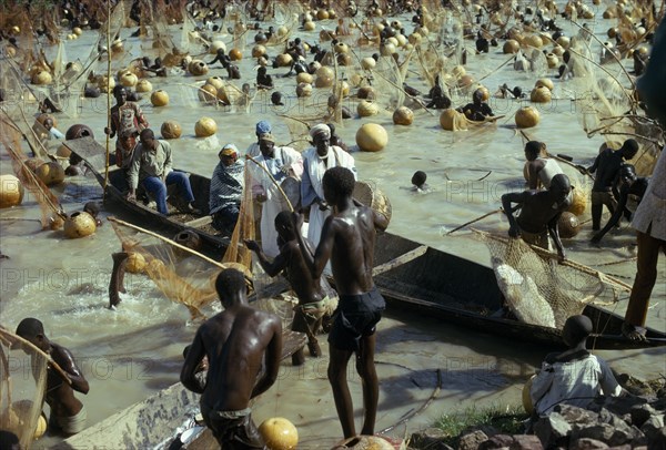 NIGERIA, North, Argungu, View over mass of men with nets in the muddy water for the Fishing Festival with men dressed in white on a boat