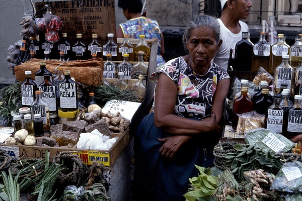 PHILIPPINES, Luzon, Manila, Woman selling various medicines on market stall.