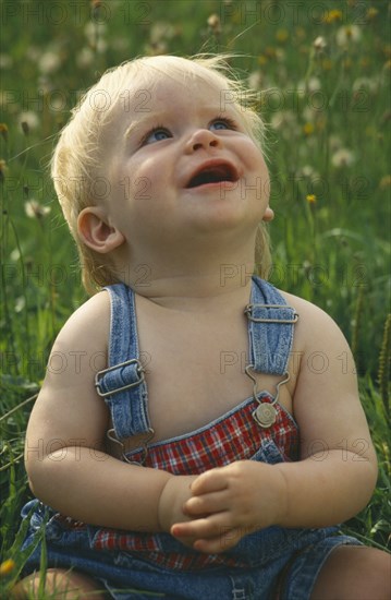 CHILDREN, Babies, One year old baby boy sitting in long grass and looking upwards