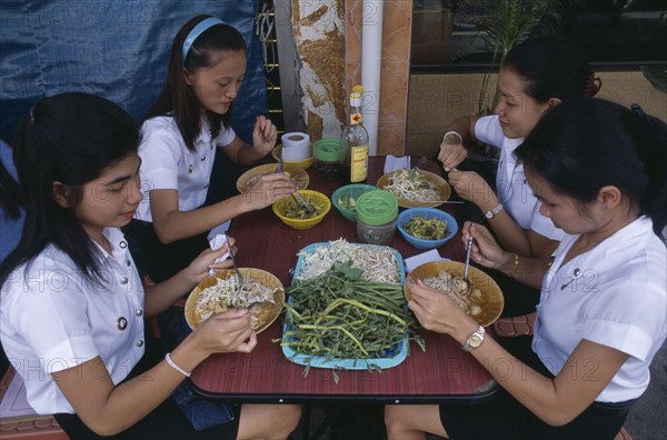 THAILAND, Bangkok, Group of schoolgirls eating lunch at street stall.