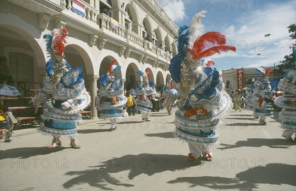 BOLIVIA, Oruro, Carnival masqueraders in colourful animal costumes in a street lined with colonial buildings