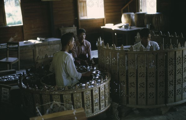 MYANMAR, Mandalay, Musicians playing classical musical instruments comprising of drums and percussion instruments in an elaborately carved circle. Pat Waing