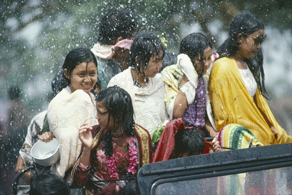 MYANMAR, Mandalay, Thingyan Buddhist Water Festival.  Group of young girls in back of truck drenched in spray of water.