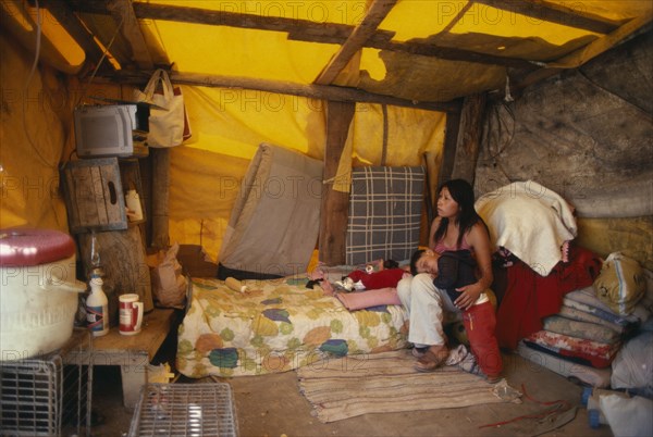 USA, New Mexico, Navajo Reservation summer camp.  Woman and children inside tent watching television.