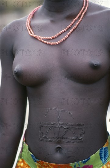 SUDAN, Scarification, Symmetrical pattern of raised scars decorate the abdomen of a young Dinka woman