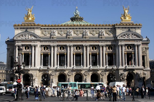 FRANCE, Ile de France, Paris, The Opera Garnier columned facade with golden statues a top and crowd of people in front