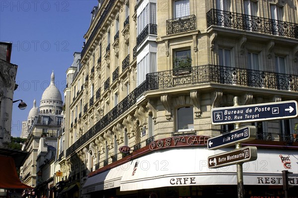 FRANCE, Ile de France, Paris, Corner cafe  and street signs with the domes of the Sacre Coeur in the distance