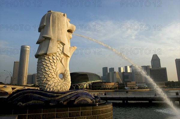 SINGAPORE, Merlion, Merlion statue spouting water over Singapore River in evening light with the city skyline beyond