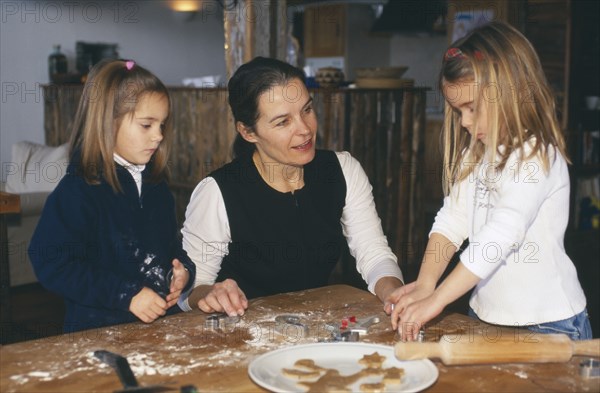 FAMILY RELATIONS, Parents, Mother, Woman making gingerbread cookies with her two young daughters.