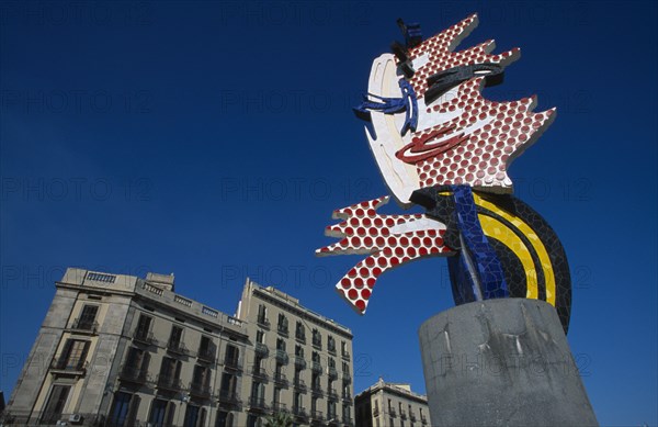 SPAIN, Catalonia, Barcelona, Colourful modern sculpture with mosaic detail.  Traditional architecture behind at the entrance to Port Vell.