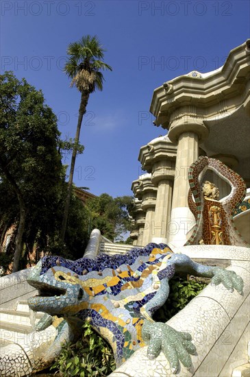 SPAIN, Catalonia, Barcelona, Gaudi dragon covered in brightly coloured tiles on the steps in Parc Guell
