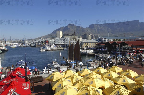 SOUTH AFRICA, Western Cape, Cape Town, View over the waterfront area with brightly coloured umbrellas in the foreground and Table Mountain in the background