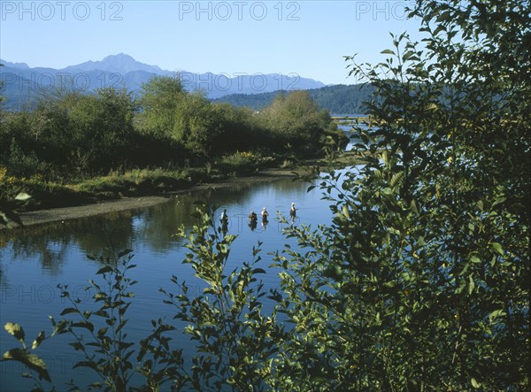 USA, Washington State, Mason, Union. View over the Skokomish River with men fishing for salmon.