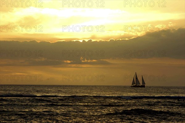 USA, Hawaii, Honolulu, Sunset over the sea with passing sail boat