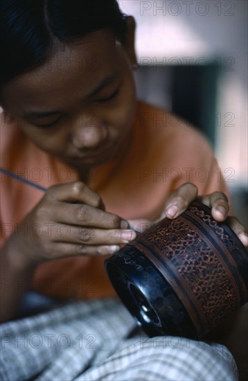 MYANMAR, Bagan, Woman applying lacquer to wood in factory workshop.