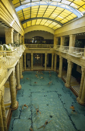 HUNGARY, Budapest, Gellert Baths.  Interior with bathers in swimming pool lined with carved pillars and with domed glass roof above.