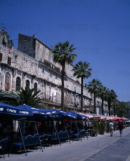 CROATIA, Split, The restored walls of the Diocletian Palace with umbrella coverred cafe tables on the pavement